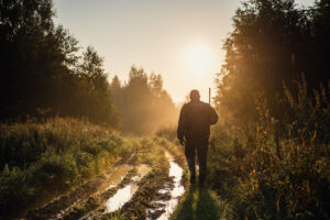 hunter walking through forest at dawn