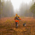 hunter walking through forest with dog