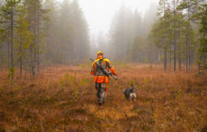 hunter walking through forest with dog