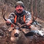 A man poses with an antelope he caught