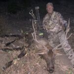 A hunter poses with his catch and bow