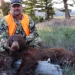 A man poses with a bear he successfully hunted at Elk Ridge Outfitters