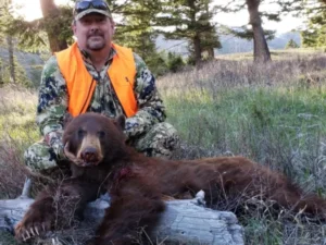 A man poses with a bear he successfully hunted at Elk Ridge Outfitters