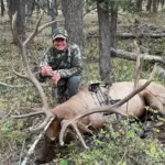 An Elk Ridge Outfitters hunter poses with his kill during an archery hunting