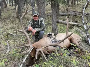 An Elk Ridge Outfitters hunter poses with his kill during an archery hunting